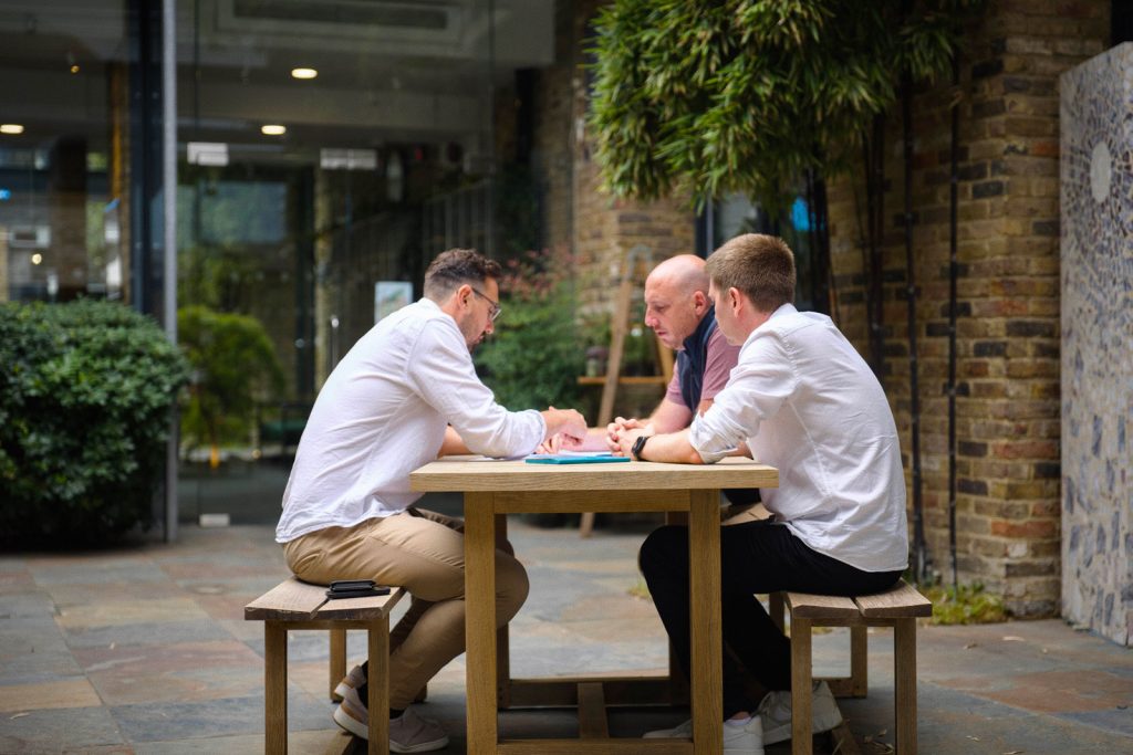 Studio80six team discussing a project around a courtyard table.